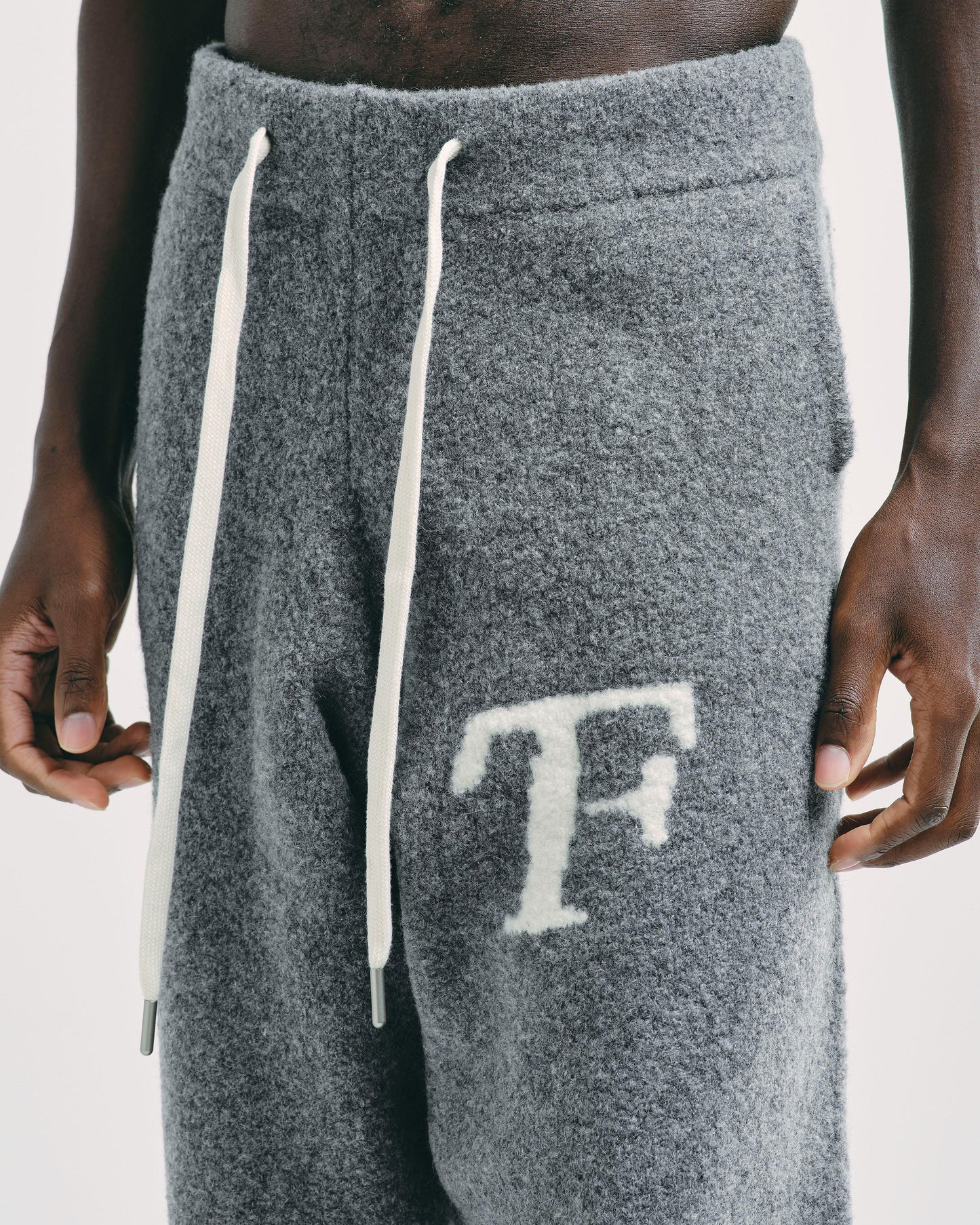 Close-up of men’s dim grey knitted joggers, showcasing fine knit texture and adjustable drawstring detail.
