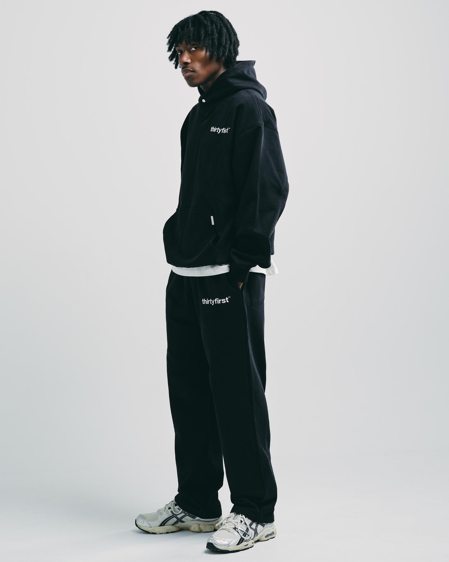 Man wearing black heavyweight hoodie with matching black straight-leg joggers, styled casually for everyday wear