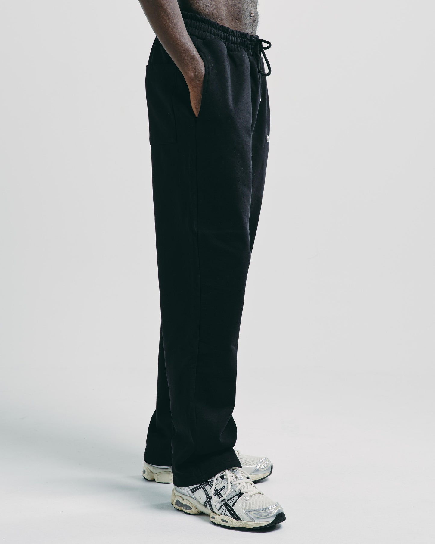 Side view of men’s black cotton tracksuit bottoms, featuring straight leg design and ribbed ankle cuffs